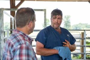 Dr. Roger Thomas, one of the owners of Thomas and England Veterinary Services in Smiths Grove, talks with Jason Smith of WPH Farms in Allen County about a calf’s healing from pink eye on Friday afternoon, June 21, 2024. Thomas said he travels far and wide to accommodate the high demand for large animal care as the Kentucky Rural Veterinary Loan Repayment Program, a new vet student loan repayment program approved by the state legislature this year that offers up to $87,500 in loan repayments over five years to vets who agree to practice on livestock in underserved rural areas or other shortage areas, aims to make a dent in a decades-long rural large animal vet shortage. (Grace Ramey McDowell, Bowling Green Daily News)