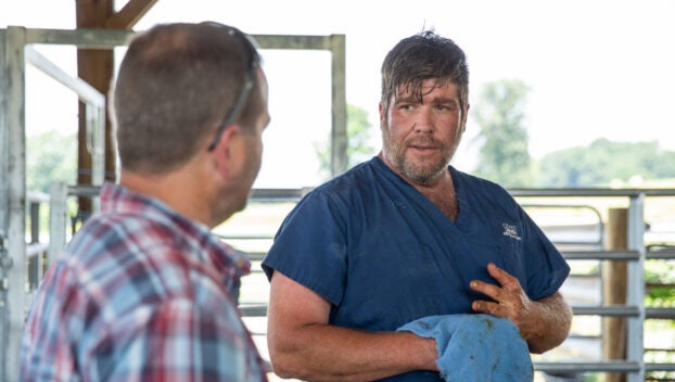 Dr. Roger Thomas, one of the owners of Thomas and England Veterinary Services in Smiths Grove, talks with Jason Smith of WPH Farms in Allen County about a calf’s healing from pink eye on Friday afternoon, June 21, 2024. Thomas said he travels far and wide to accommodate the high demand for large animal care as the Kentucky Rural Veterinary Loan Repayment Program, a new vet student loan repayment program approved by the state legislature this year that offers up to $87,500 in loan repayments over five years to vets who agree to practice on livestock in underserved rural areas or other shortage areas, aims to make a dent in a decades-long rural large animal vet shortage. (Grace Ramey McDowell, Bowling Green Daily News)